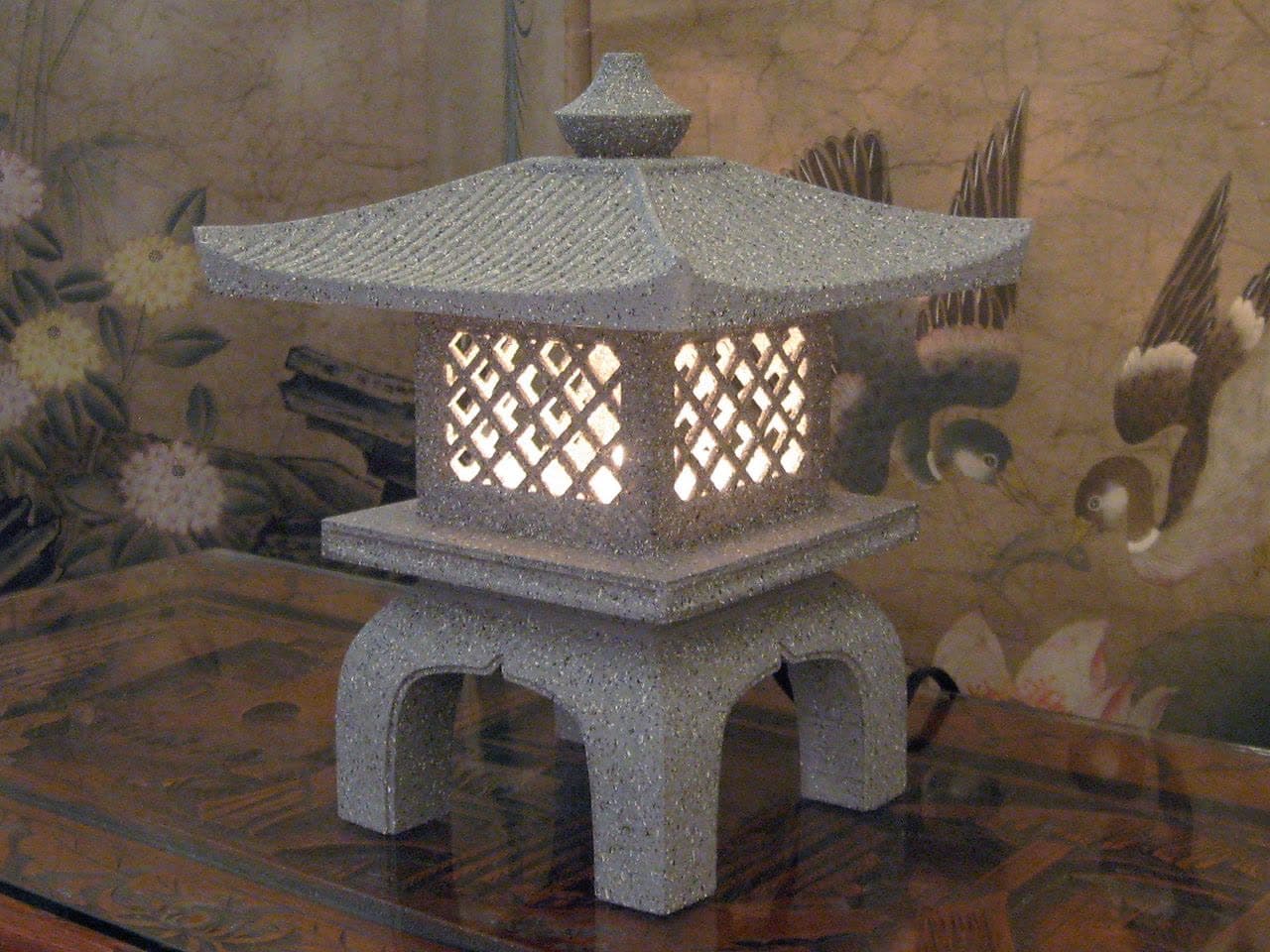 A garden lantern in a stone-textured finish, lit at night.